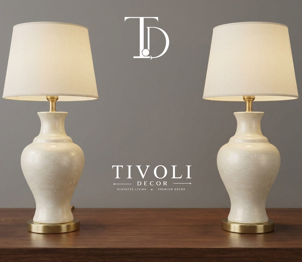 Pair of branded Tivoli Decor luxury table lamps with textured mottled cream ceramic bases and ivory fabric shades standing symmetrically on a dark wooden table.