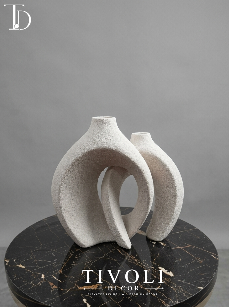 Nordic textured off-white interlocking ceramic vase set by Tivoli Decor, a premium abstract decoration piece for living room coffee tables in Pakistan.Close-up showing the granular sand-textured stone patina and nested silhouette of the twin off-white ceramic vase sculpture by Tivoli Decor.