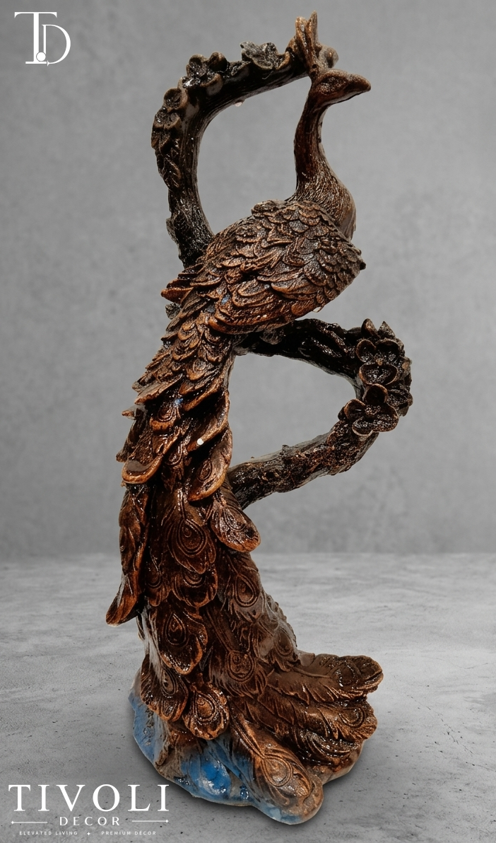 Antique bronze peacock sculpture perched on branch with blue base accent - Tivoli Decor Pakistan. Vintage antique bronze peacock statue on a tree branch by Tivoli Decor, a premium luxury decoration piece for living room console tables in Pakistan.