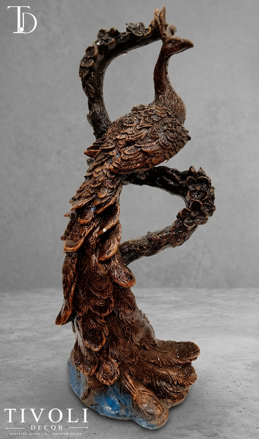 Antique bronze peacock sculpture perched on branch with blue base accent - Tivoli Decor Pakistan. Vintage antique bronze peacock statue on a tree branch by Tivoli Decor, a premium luxury decoration piece for living room console tables in Pakistan.