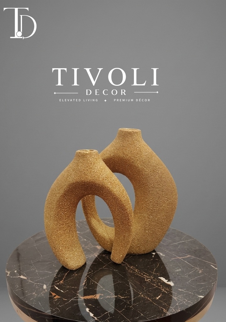 Luxury textured golden interlocking ceramic and resin vase set by Tivoli Decor, a premium abstract decoration piece for living room coffee tables in Pakistan.
Close-up showing the granular shimmering sand texture and nested design of the twin metallic gold ceramic vase sculpture by Tivoli Decor.