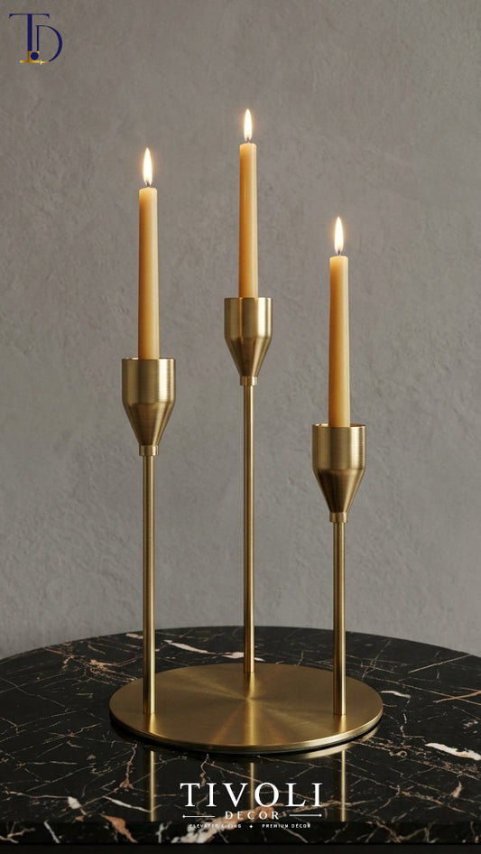 Minimalist 3-tier brushed gold candlestick holder set by Tivoli Decor, a premium luxury decoration piece holding burning taper candles in Pakistan.