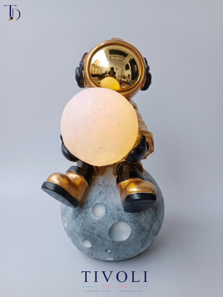 Branded Tivoli Decor luxury astronaut moon lamp holding an illuminated glowing globe while sitting on a textured grey lunar base.