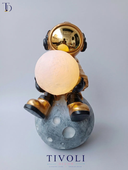 Branded Tivoli Decor luxury astronaut moon lamp holding an illuminated glowing globe while sitting on a textured grey lunar base.