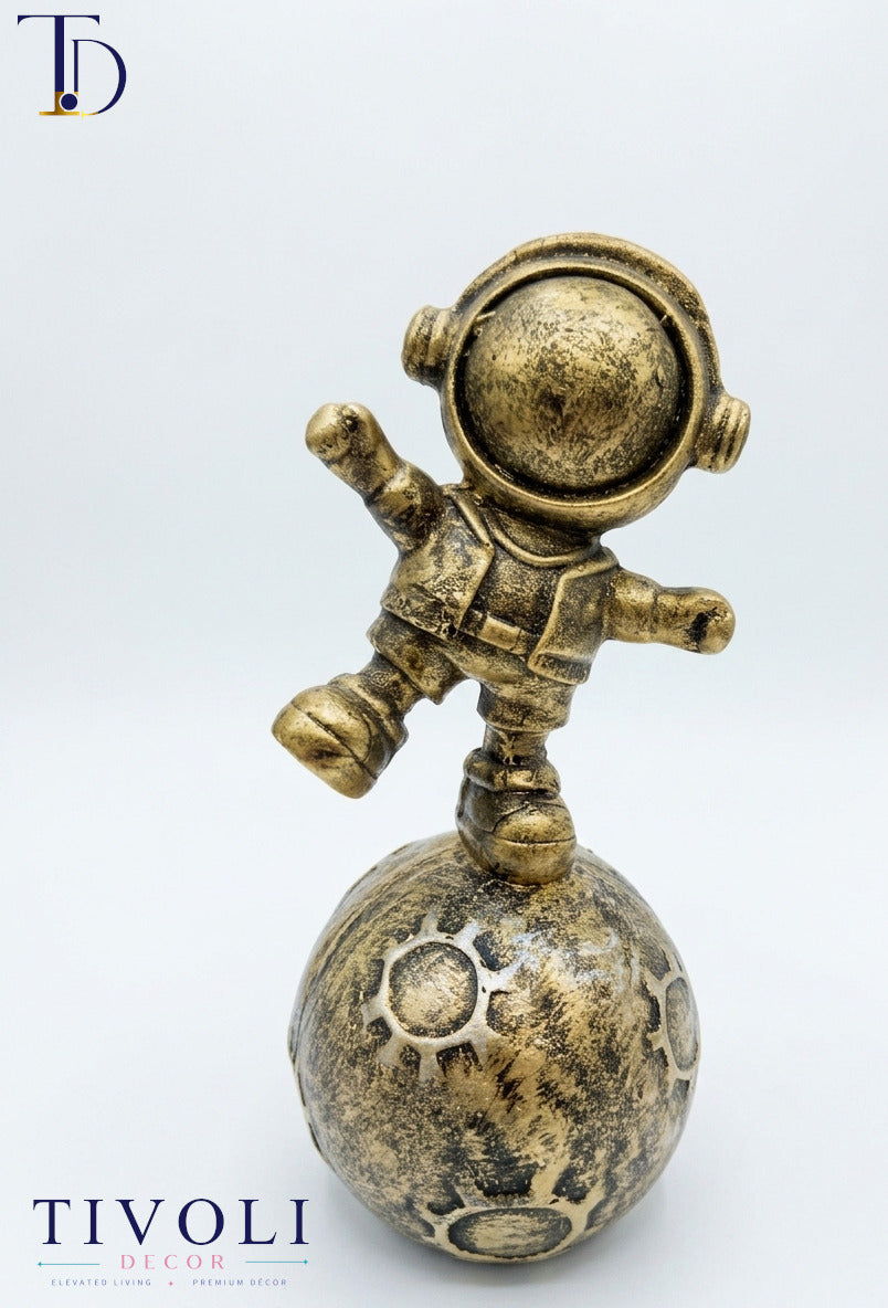 Antique golden floating astronaut statue balancing on a planet globe base by Tivoli Decor, a premium luxury table decoration piece in Pakistan.