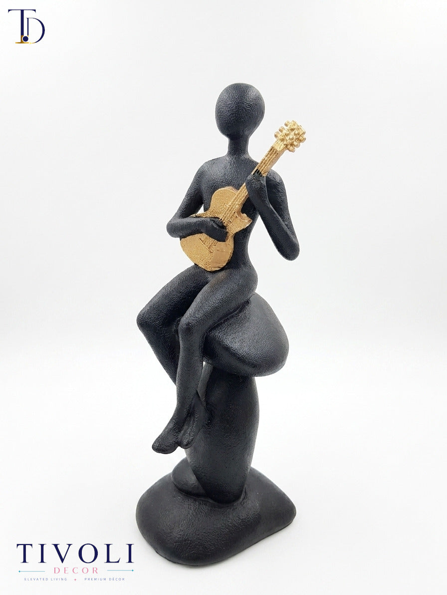 Modern volcanic black musician statue with a golden guitar by Tivoli Decor, a premium abstract decoration piece for living room console tables in Pakistan.