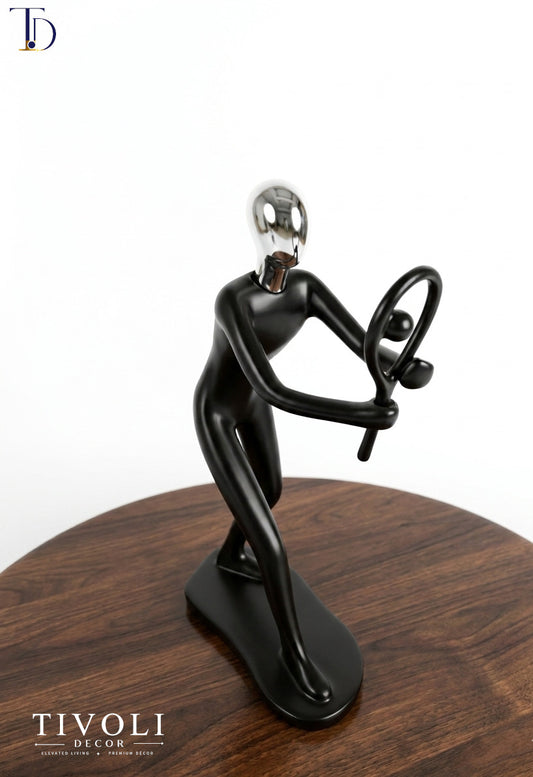 Modern matte black and chrome silver tennis player statue with racket by Tivoli Decor, a premium abstract sports decoration piece on a dark wood table in Pakistan.