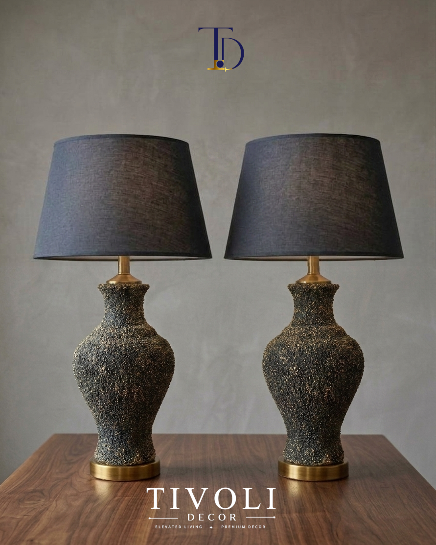 Pair of branded Tivoli Decor luxury table lamps with heavily textured charcoal volcanic stone ceramic bases and black fabric shades styled on a wood table.