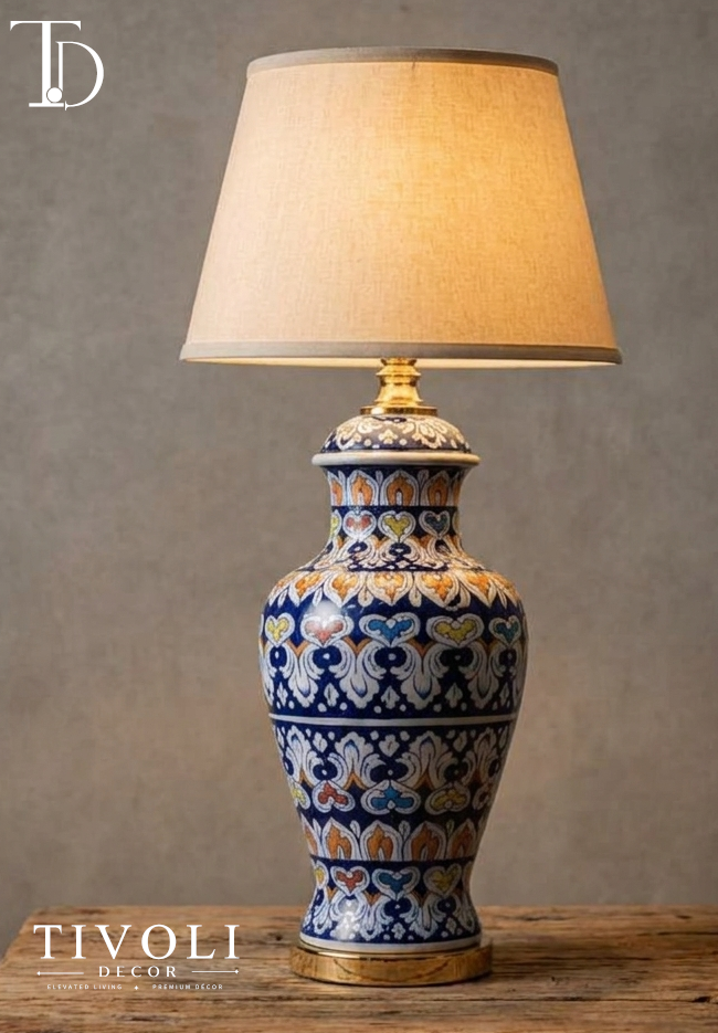 Branded Tivoli Decor luxury ceramic table lamp with an intricate hand painted blue and orange multi color royal floral ginger jar body and linen shade on a rustic wood table.