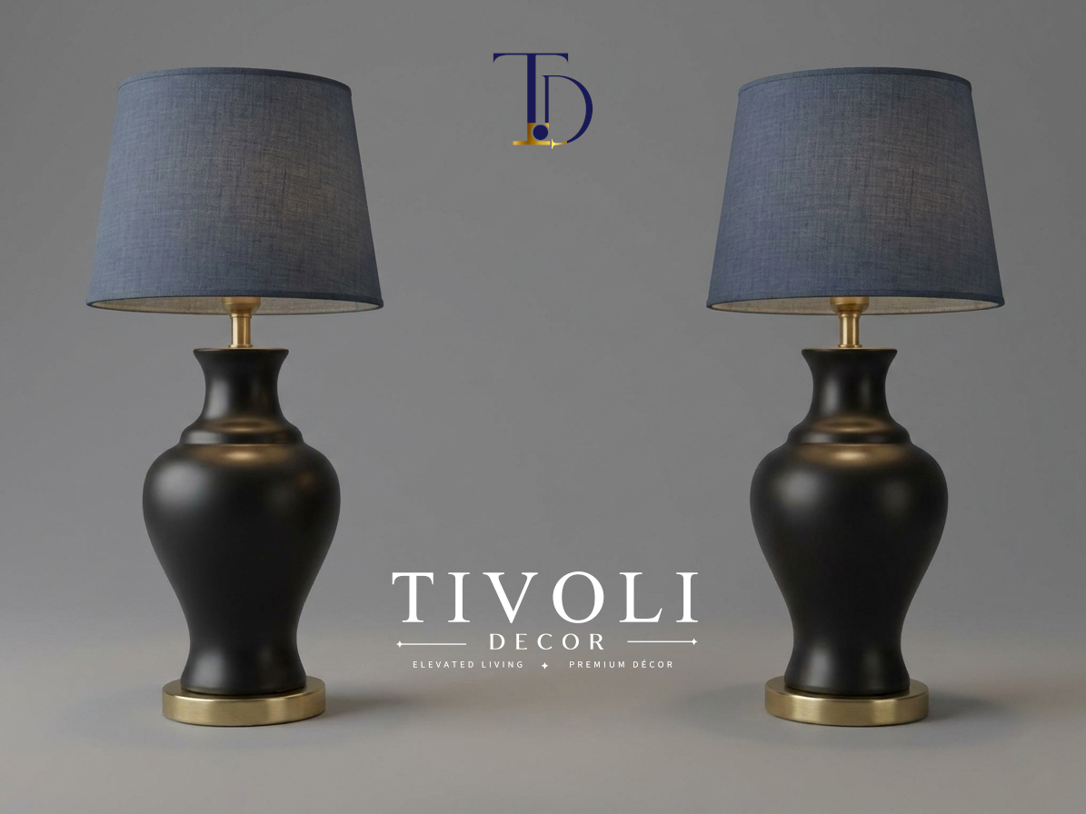 Pair of branded Tivoli Decor luxury table lamps with smooth satin matte black ceramic bases, gold pedestals, and slate blue linen fabric shades against a grey background.