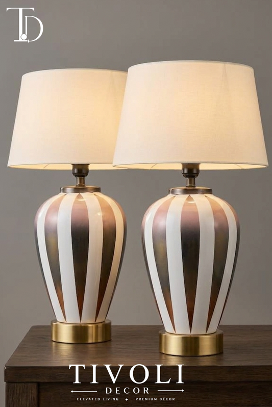 Pair of branded Tivoli Decor luxury table lamps with striped metallic ombre ceramic bases, brushed brass pedestals, and cream fabric shades on a dark wood table.