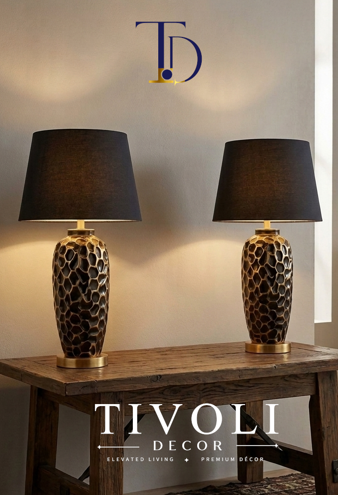 Pair of Tivoli Decor luxury textured ceramic table lamps with black fabric shades lit symmetrically on a metal console table against a wood paneled wall