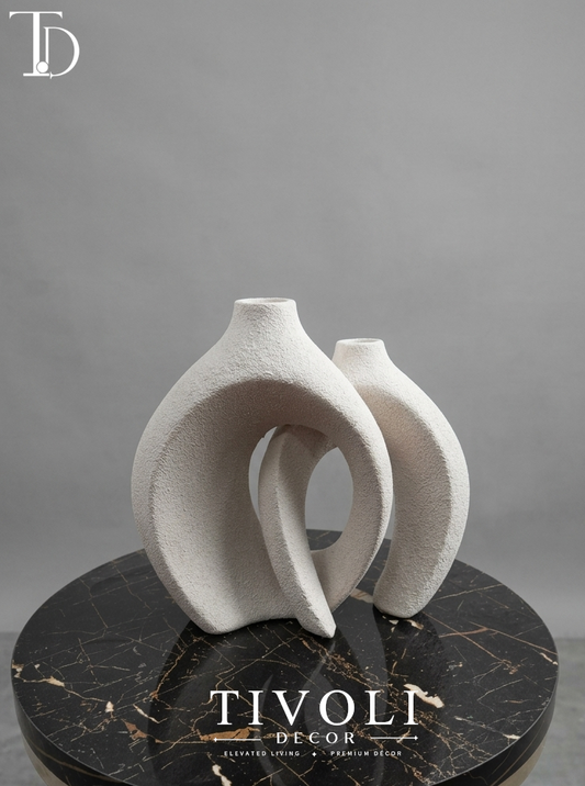 Nordic textured off-white interlocking ceramic vase set by Tivoli Decor, a premium abstract decoration piece for living room coffee tables in Pakistan.Close-up showing the granular sand-textured stone patina and nested silhouette of the twin off-white ceramic vase sculpture by Tivoli Decor.